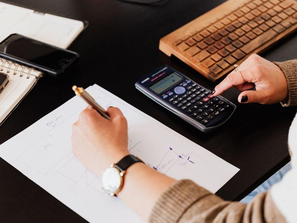 Someone working through numbers with a calculator and notepad