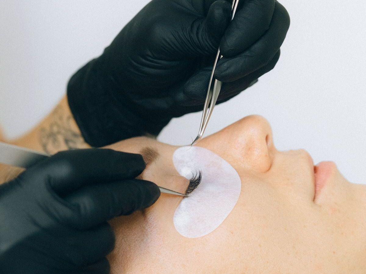 A technician working on a client's lashes with tweezers