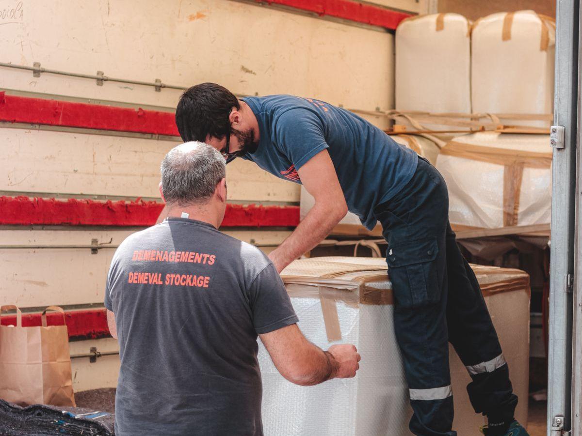 Two movers unloading boxes from the back of a truck